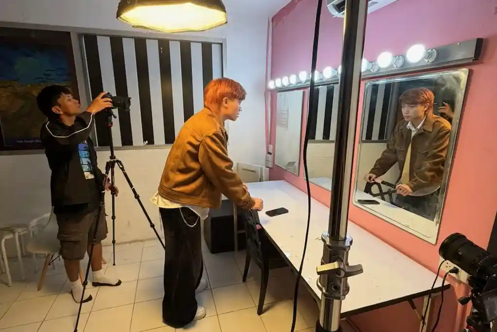 Two young media makers filming in a dressing room during a music video shoot