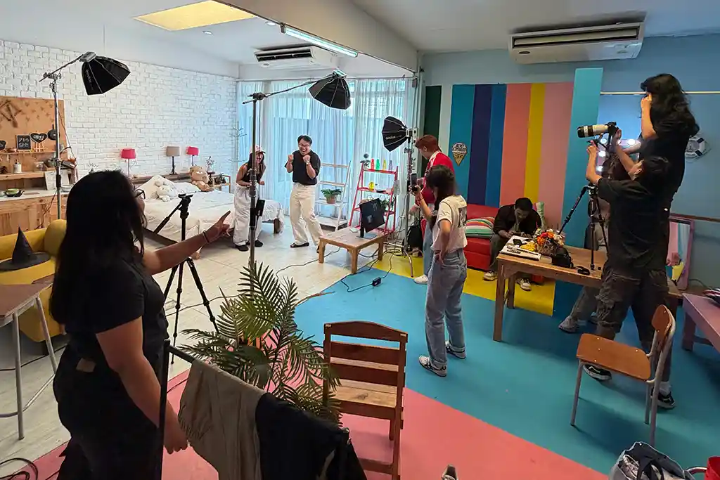 A crew of young media makers shooting a music video on a colourful studio set